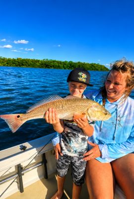 Mother and son holding a redfish on a Florida backcountry fishing charter boat